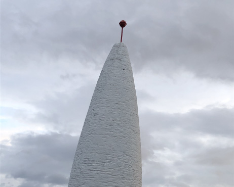 White beacon pointing upwards to the sky on an overcast day